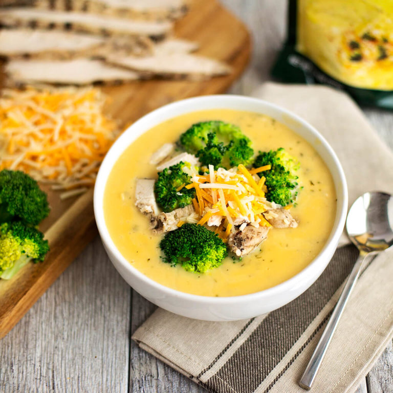 Broccoli cheddar soup with chicken and cheese topping, served in a white bowl.