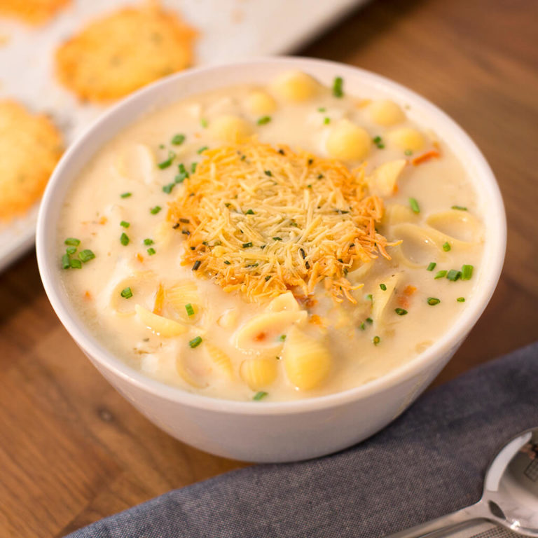 Creamy chicken noodle soup topped with cheese and chives, served with biscuits.