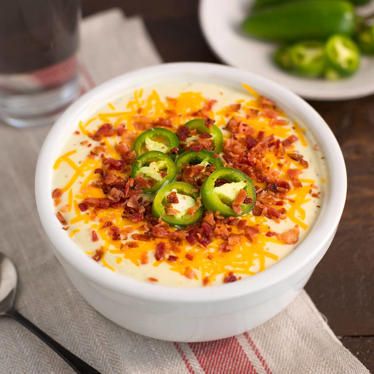 Hearty bacon and cheddar soup topped with jalapenos, perfect for food blog recipes.