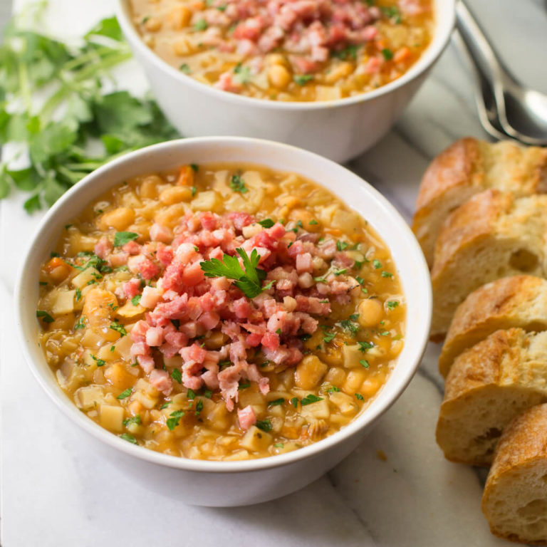 Hearty split pea soup with ham garnish and fresh bread on the side. Warm, nutritious meal.
