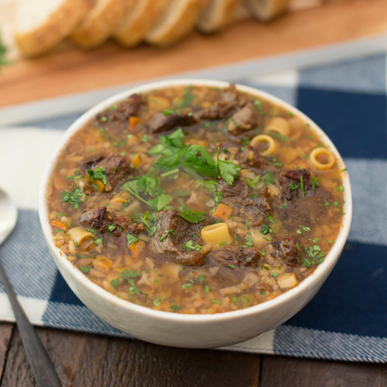 Hearty beef and vegetable soup in a bowl, garnished with parsley - homemade comfort food.